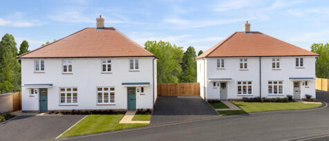 Two modern semi-detached houses with white exteriors and red-tiled roofs, surrounded by greenery and