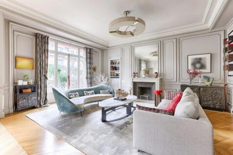 Elegant living room with a classic design, featuring stylish furniture, a fireplace, and large windows with curtains.