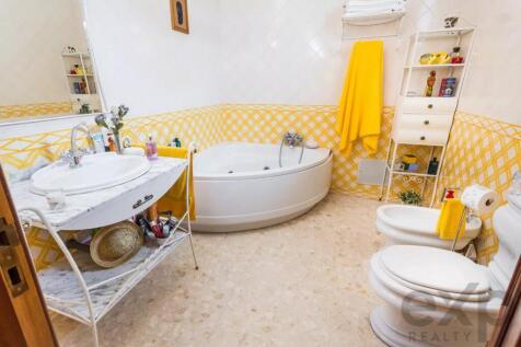 Bathroom with yellow decor, containing a corner ba