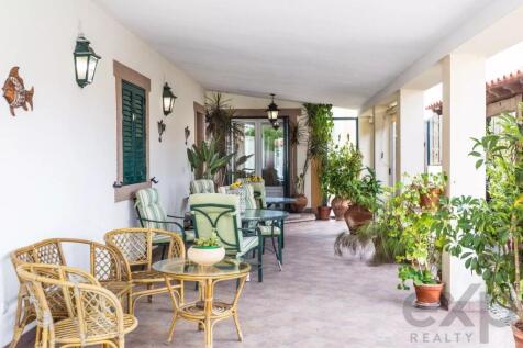 A covered patio with wicker and metal furniture su