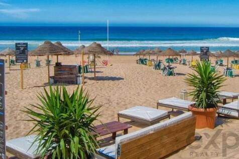 Sunny beach with lounge chairs, umbrellas, calm at