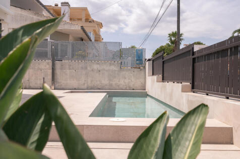 L-shaped pool hidden behind the fence by the street entrance