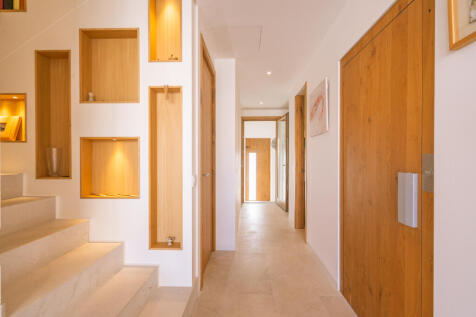 View of the entrance area with staircase on the left, elevator behind solid wood doors on the right, and guest WC