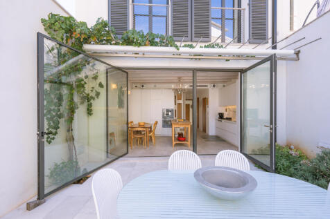 View from the patio to the rear façade of the house with elegant shutters