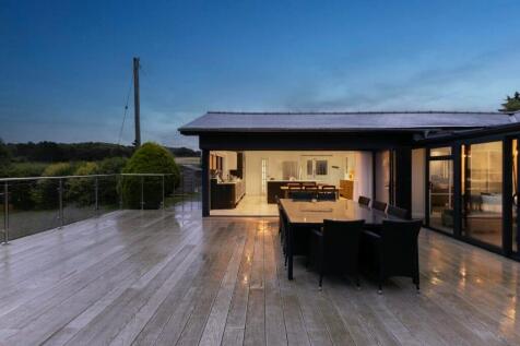 Evening terrace dining with illuminated kitchen ba