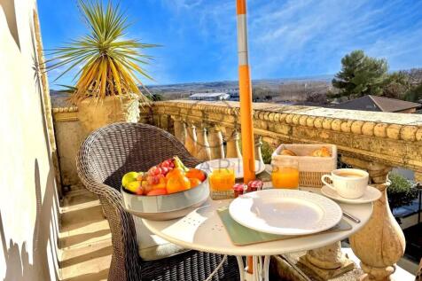 A sunny balcony with a wicker chair, a small table