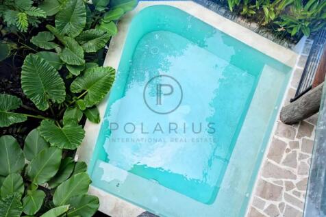 A small, turquoise pool surrounded by lush green p