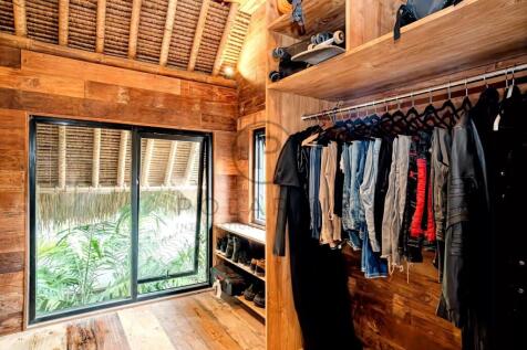 A cozy wooden walk-in closet with clothing hanging