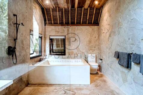 A rustic bathroom features stone walls, a white tu