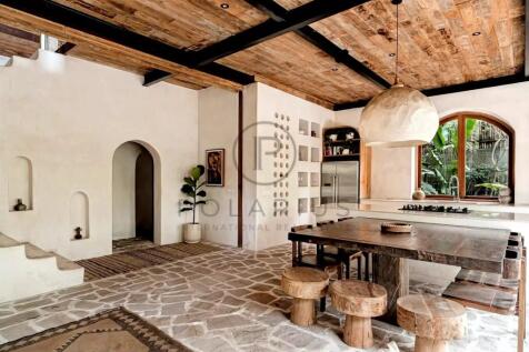 A rustic kitchen with stone flooring, wooden ceili