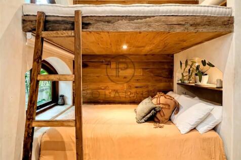 Cozy loft bed with wooden beams, a ladder, and a w