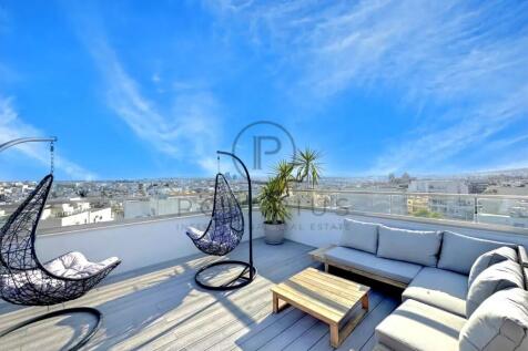 A rooftop terrace with hanging chairs, a sofa, and