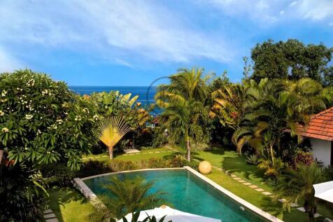 A tropical garden features a pool surrounded by lu