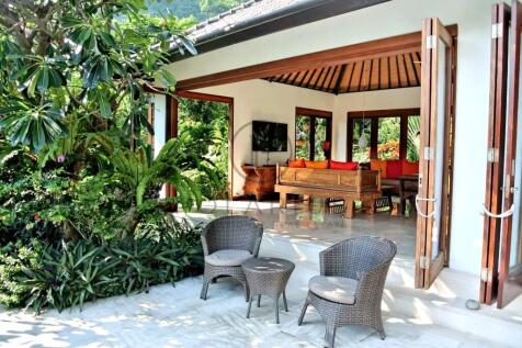A tropical open-air living area with wicker chairs
