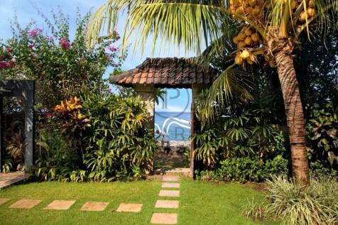 A tropical garden path leads through a leafy archw