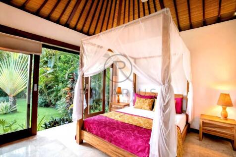 A bright, tropical bedroom featuring a canopy bed 