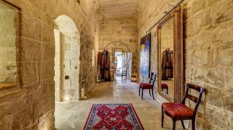 A rustic stone hallway features a red patterned ru