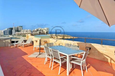 A rooftop terrace with a dining table, chairs, and