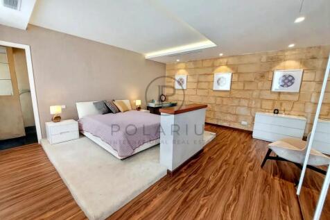 A modern bedroom with wooden flooring, a large bed