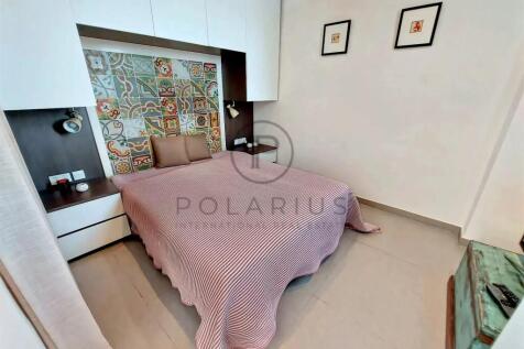 A cozy bedroom features a bed with a pink striped 