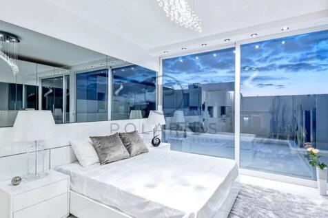 A modern, minimalist bedroom features a large bed,