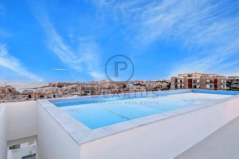 A rooftop infinity pool overlooks a cityscape, wit