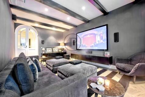 A modern home theater room features a large screen