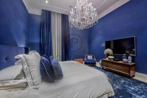 A luxurious bedroom with vibrant blue walls, a lar
