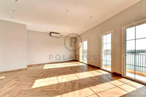 A spacious, sunlit empty room with wooden floors,
