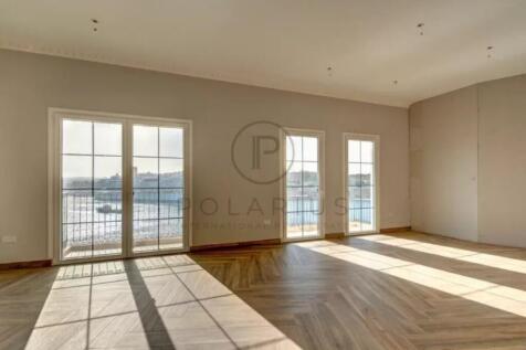 Sunlit empty room with large windows and parquet f