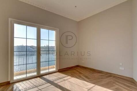 A bright, empty room with wooden flooring and a la
