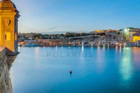 A scenic view of a calm harbor at dusk, with histo