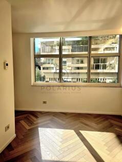 A bright, empty room with wood flooring and large