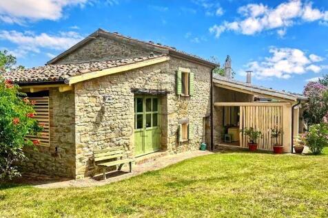 A charming stone house with green shutters sits in