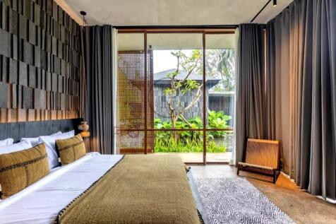 A modern bedroom with large glass doors opens to a