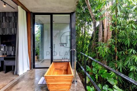 A modern bathroom features a wooden bathtub on a b