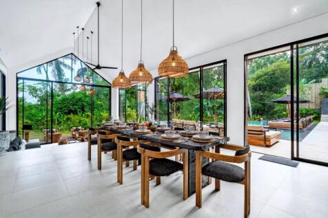A modern dining area with wooden furniture, pendan