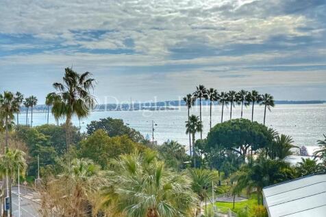 A scenic coastal view features palm trees, a calm 