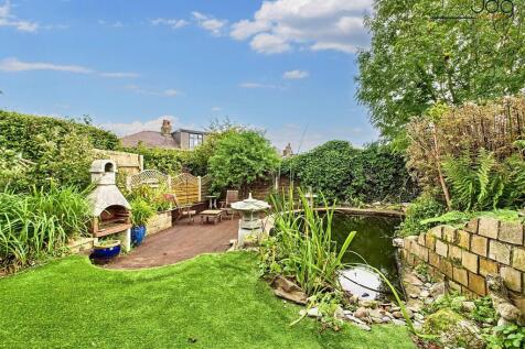 Spacious garden with a mixed of decking, artificial lawn and a pond