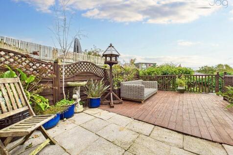 Spacious garden with a mixed of decking, artificial lawn and a pond