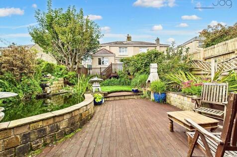 Spacious garden with a mixed of decking, artificial lawn and a pond