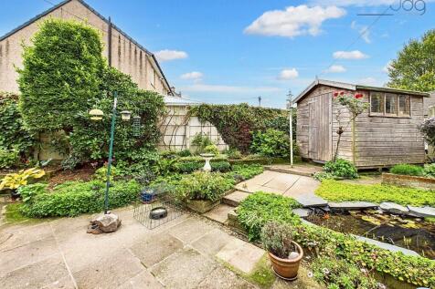Spacious Flagged Garden with Mature Shrubs and Pond