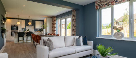 Modern open-plan living room with white sofa, blue walls, large windows, and a view of neighbouring