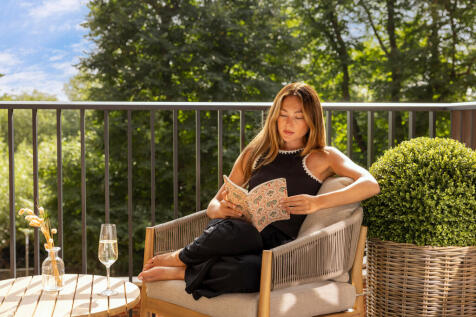 woman reading a book whilst sat on her balcony