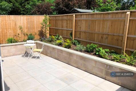 Sunny Patio By Day. Play Park Path Behind Fence.