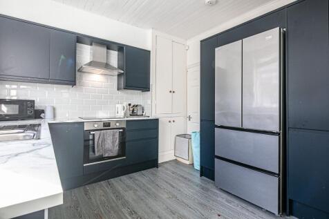 Modern fitted kitchen with dark cabinetry, slee...