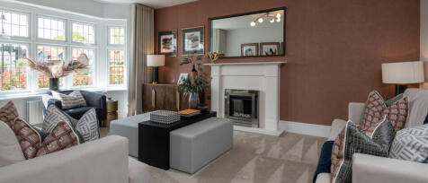 Modern living room with large bay window, patterned cushions, white sofa, black armchair, and a fire