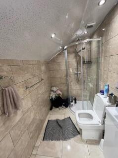 Tiled bathroom with a corner glass shower enclo...