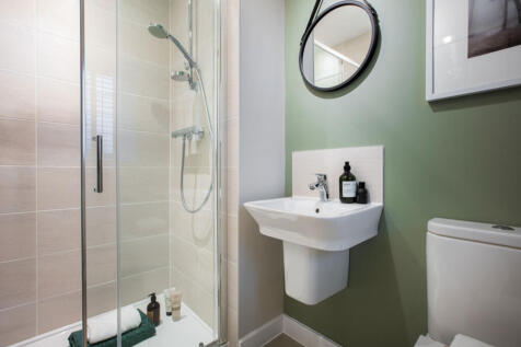 A modern bathroom with a glass shower enclosure, a white pedestal sink