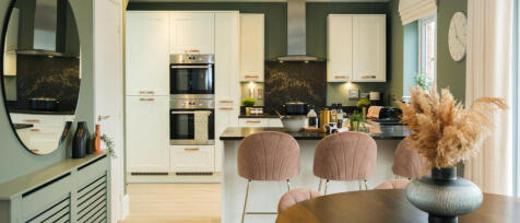 Modern kitchen with cream cabinets, black countertops, and pastel pink bar stools, decorated with pl